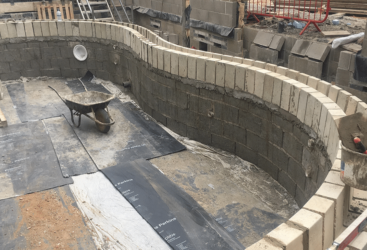 A swimming pool under construction with a wheelbarrow inside.