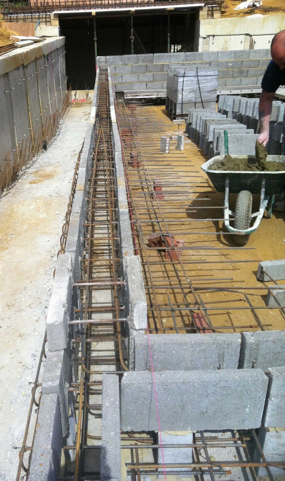 Concrete blocks and rebar form the shell of a swimming pool under construction.