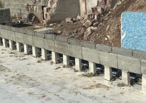 Concrete blocks being used to construct a wall foundation at a construction site.