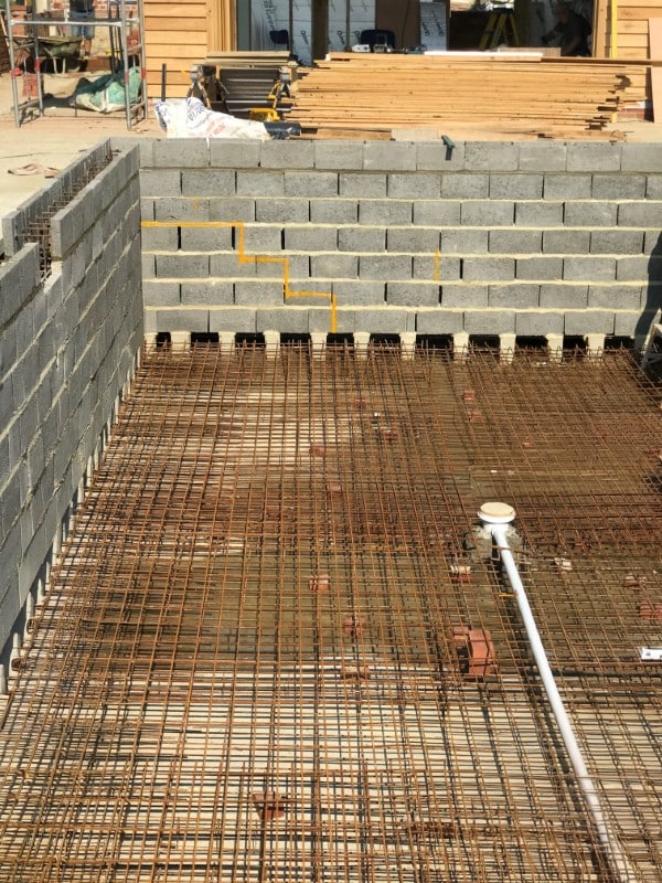 Concrete block walls and steel rebar foundation under construction at a building site.