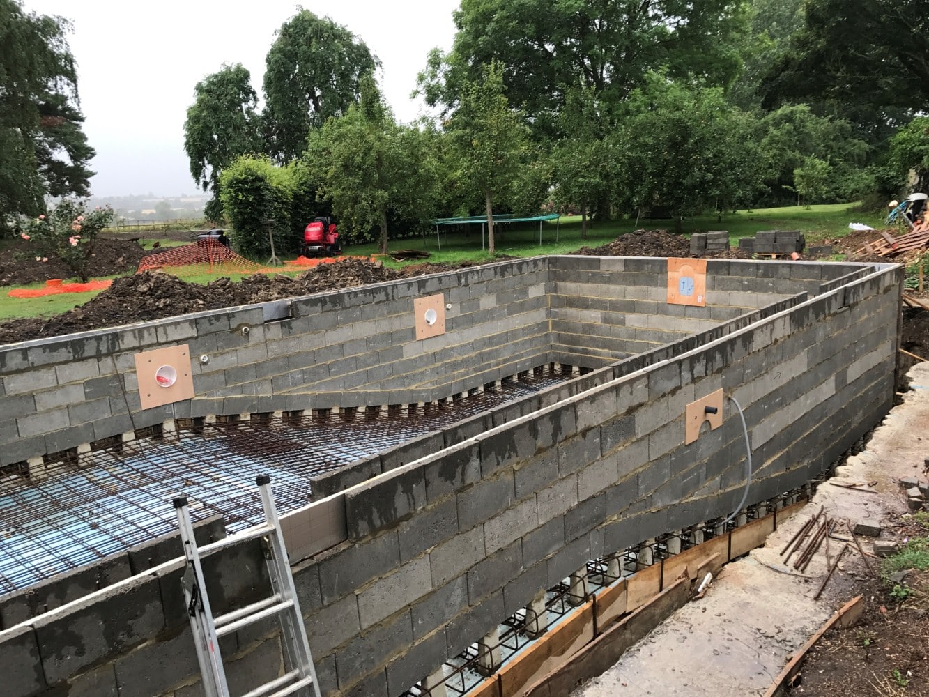 A concrete swimming pool under construction with cinder block walls and steel rebar.